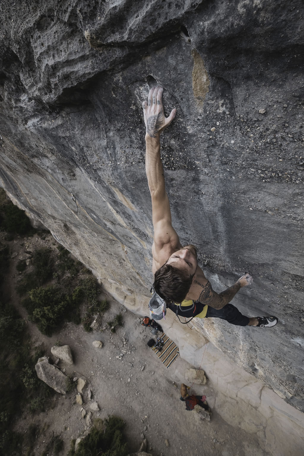 climber Felipe Camargo seen from above gripping the rock wall with one hand on top